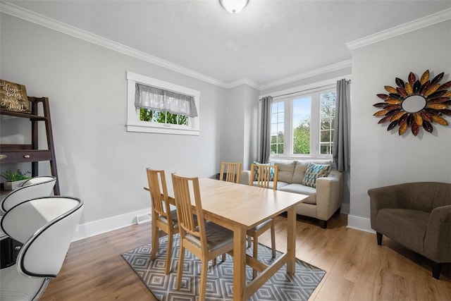 dining space with baseboards, ornamental molding, and light wood-type flooring