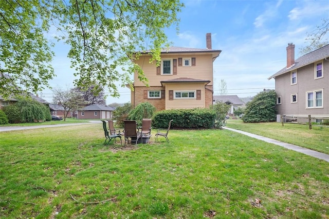 rear view of property featuring a lawn and a chimney