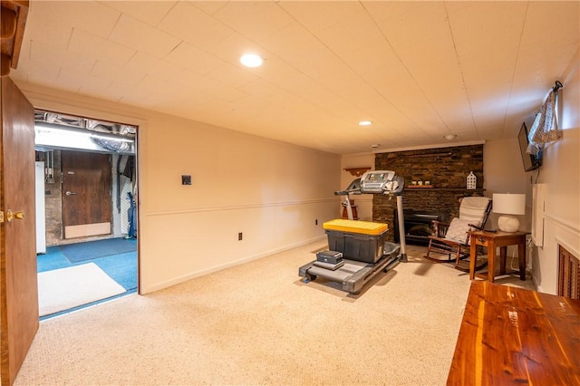 exercise room featuring carpet floors, recessed lighting, and a stone fireplace