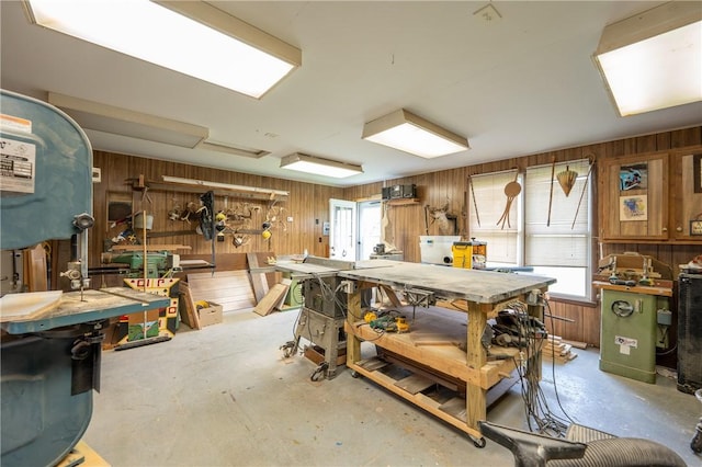 misc room with wooden walls, a workshop area, and unfinished concrete floors