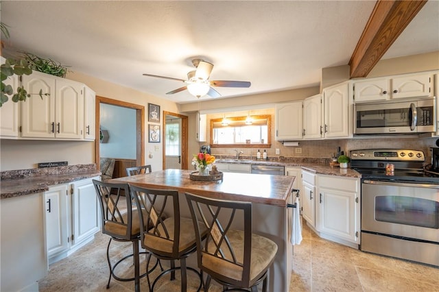 kitchen with stainless steel appliances, ceiling fan, white cabinetry, and a sink