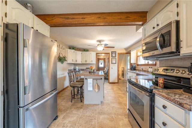 kitchen featuring a kitchen breakfast bar, a kitchen island, a ceiling fan, appliances with stainless steel finishes, and white cabinetry