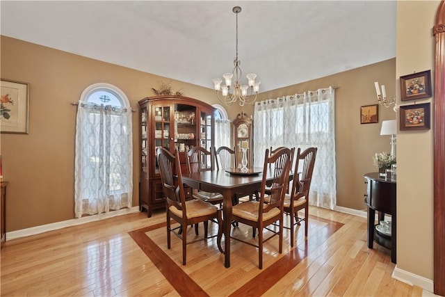 dining room with plenty of natural light, baseboards, a notable chandelier, and light wood-type flooring