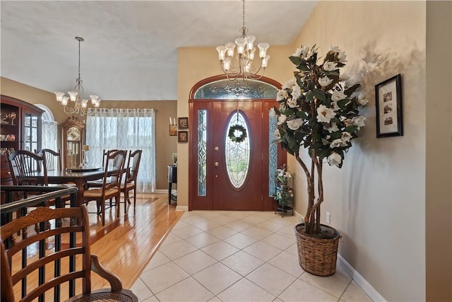 foyer entrance featuring an inviting chandelier, baseboards, and light tile patterned flooring