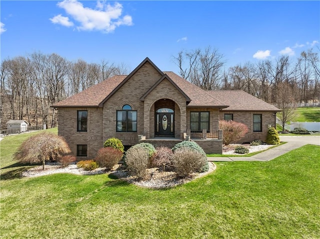view of front of property with brick siding, a shingled roof, and a front yard