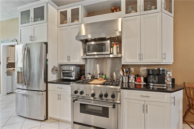 kitchen featuring a toaster, white cabinets, light tile patterned flooring, stainless steel appliances, and wall chimney exhaust hood