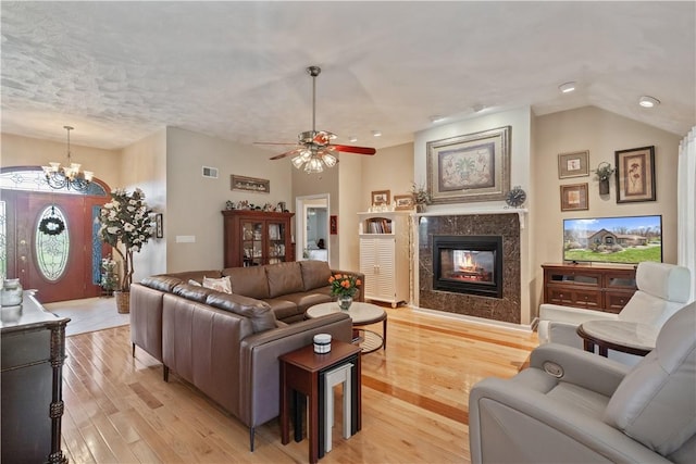 living room featuring visible vents, recessed lighting, a high end fireplace, light wood-style flooring, and ceiling fan with notable chandelier