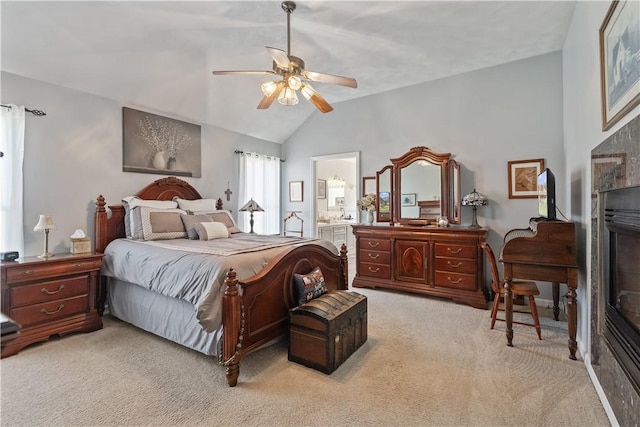bedroom featuring ceiling fan, a tile fireplace, lofted ceiling, ensuite bathroom, and light carpet