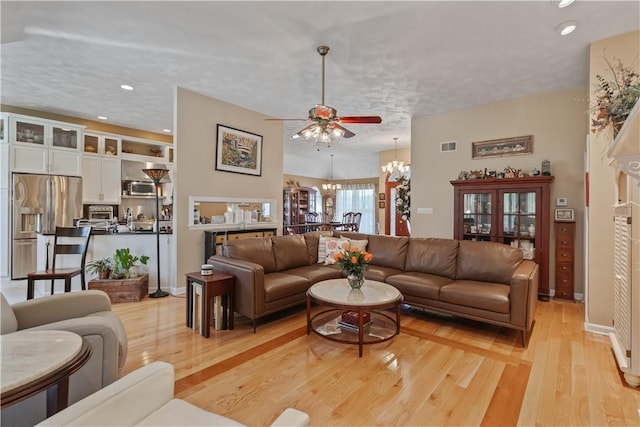 living area featuring light wood-style floors, recessed lighting, ceiling fan with notable chandelier, and visible vents