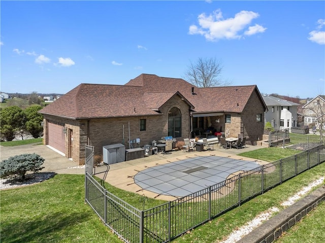 rear view of house with a fenced backyard, brick siding, a shingled roof, a patio area, and a yard