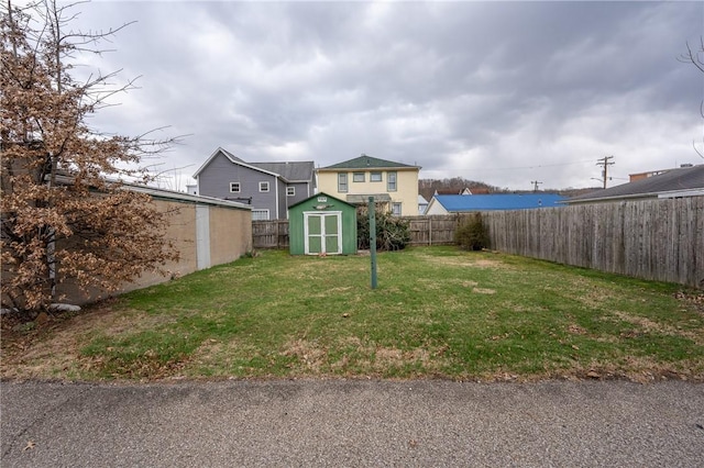 view of yard featuring a storage unit, a fenced backyard, and an outbuilding