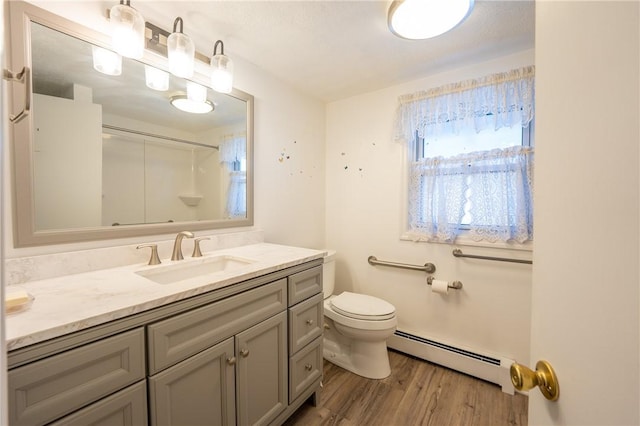bathroom with vanity, wood finished floors, toilet, walk in shower, and a baseboard radiator