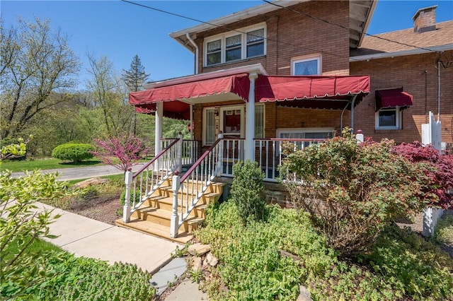 view of front of property featuring a chimney and brick siding