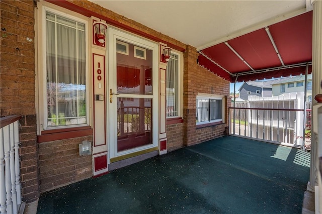 entrance to property featuring a porch and brick siding