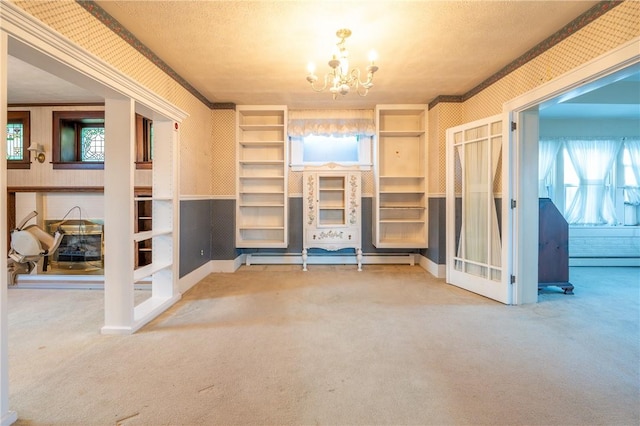 empty room featuring carpet, a chandelier, and baseboard heating