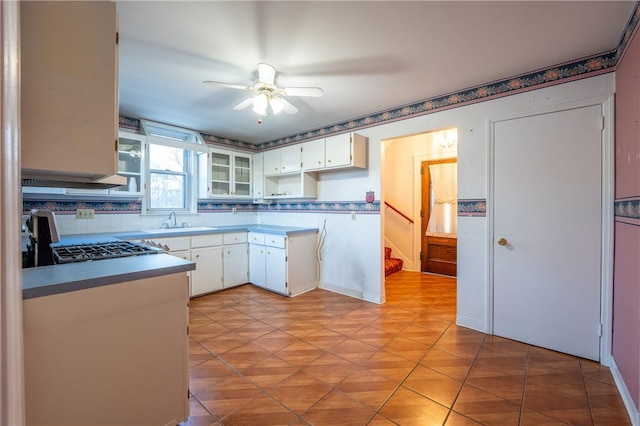 kitchen featuring a sink, range, a ceiling fan, white cabinetry, and backsplash