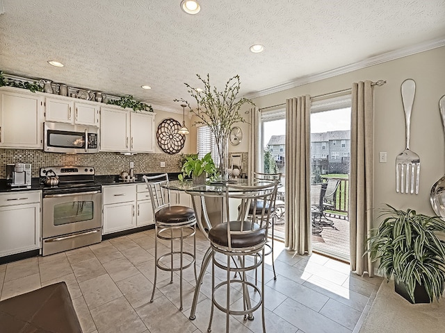 kitchen with dark countertops, appliances with stainless steel finishes, tasteful backsplash, and ornamental molding