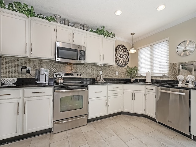 kitchen featuring ornamental molding, appliances with stainless steel finishes, white cabinets, and dark countertops