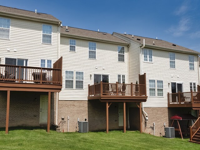 back of property with a wooden deck, a yard, central AC, and brick siding