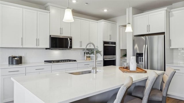 410 Barons Ct, Peters Twp, PA 15367 - kitchen with appliances with stainless steel finishes, tasteful backsplash, an island with sink, white cabinetry, and a breakfast bar area