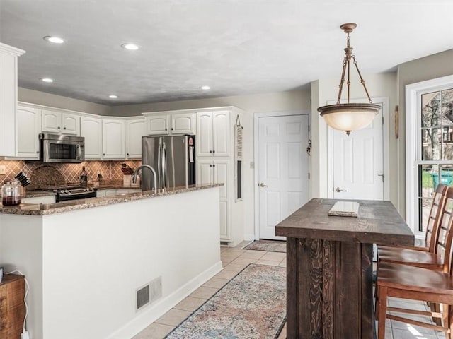 1312 Red Cut Lodge Rd, Derry Twp, PA 15650 - kitchen with visible vents, dark stone counters, tasteful backsplash, light tile patterned floors, and stainless steel appliances