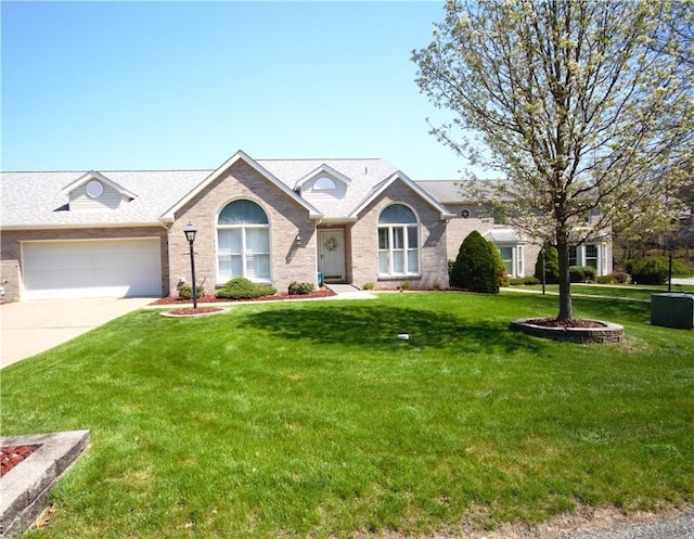single story home featuring brick siding, a front lawn, an attached garage, and concrete driveway
