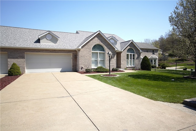 view of front of house with brick siding, an attached garage, driveway, and a front yard