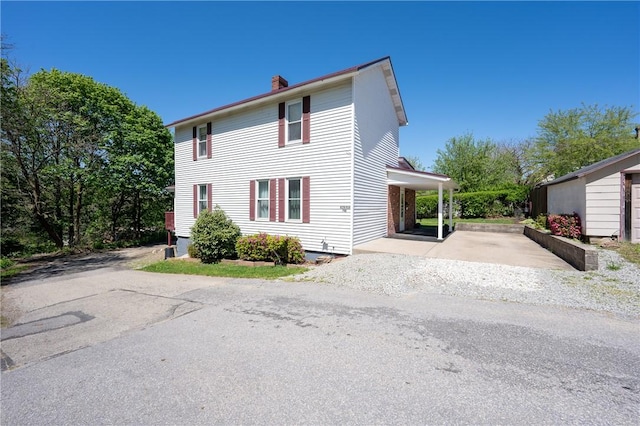 view of property exterior featuring driveway and a chimney