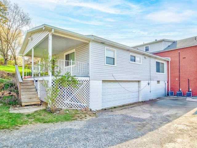 view of home's exterior featuring covered porch, driveway, stairs, and a garage