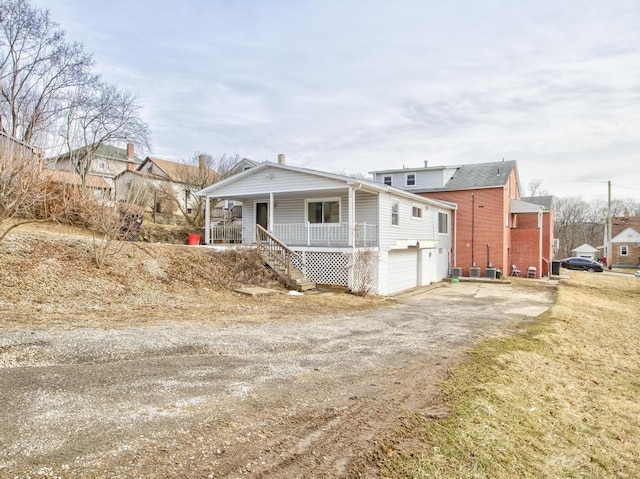 view of property exterior featuring a garage, covered porch, stairs, and driveway