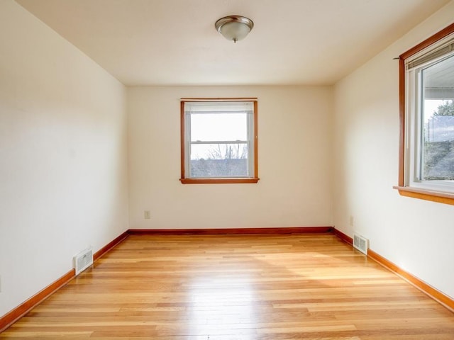 empty room featuring baseboards, light wood-style flooring, and visible vents