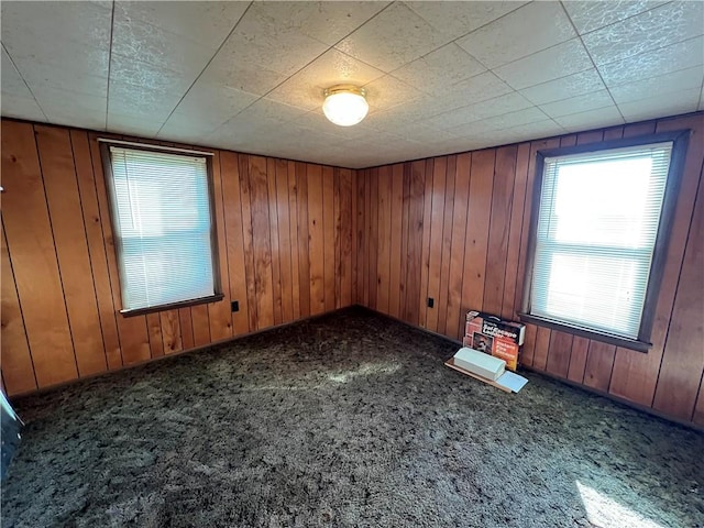 carpeted spare room featuring wood walls