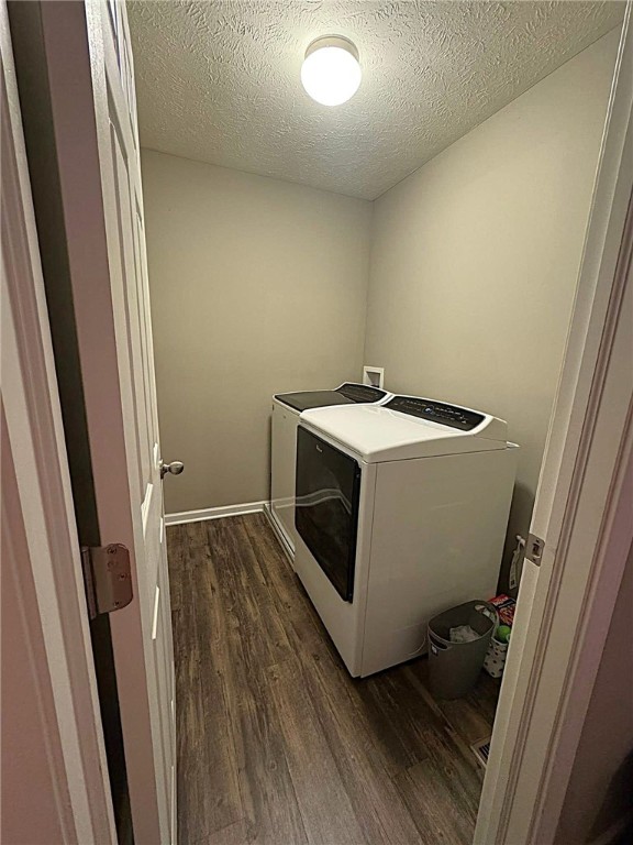 laundry area featuring laundry area, dark wood-type flooring, a textured ceiling, and washer / clothes dryer