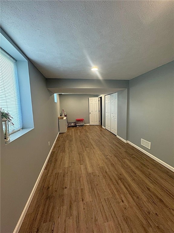 interior space with visible vents, baseboards, a textured ceiling, and wood finished floors