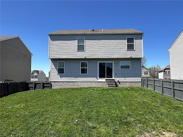 rear view of property featuring a lawn, a fenced backyard, and entry steps