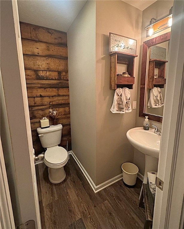 bathroom with a sink, log walls, toilet, and wood finished floors