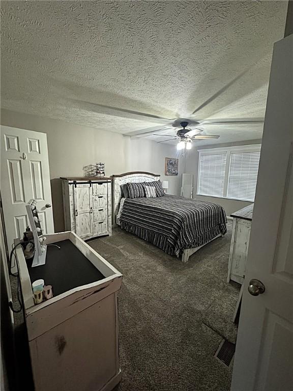 bedroom featuring carpet floors, a ceiling fan, and a textured ceiling