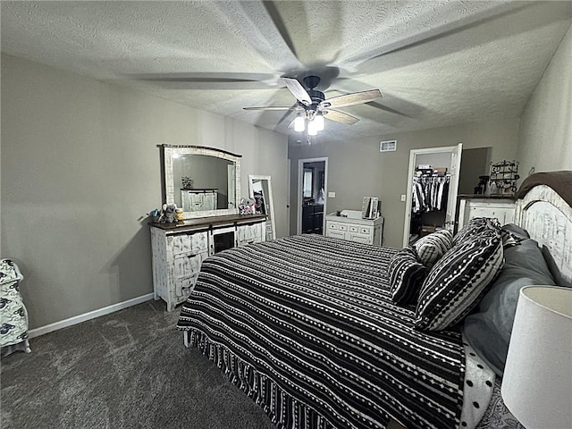 carpeted bedroom with visible vents, baseboards, a textured ceiling, a spacious closet, and a ceiling fan