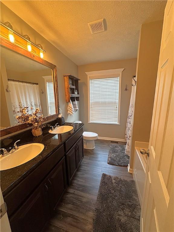 bathroom featuring a sink, wood finished floors, a textured ceiling, and visible vents