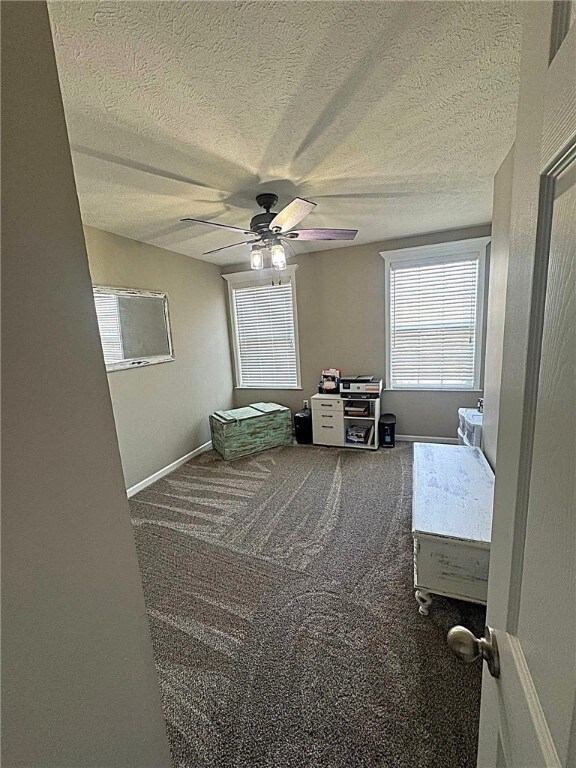 bedroom featuring baseboards, ceiling fan, carpet, and a textured ceiling