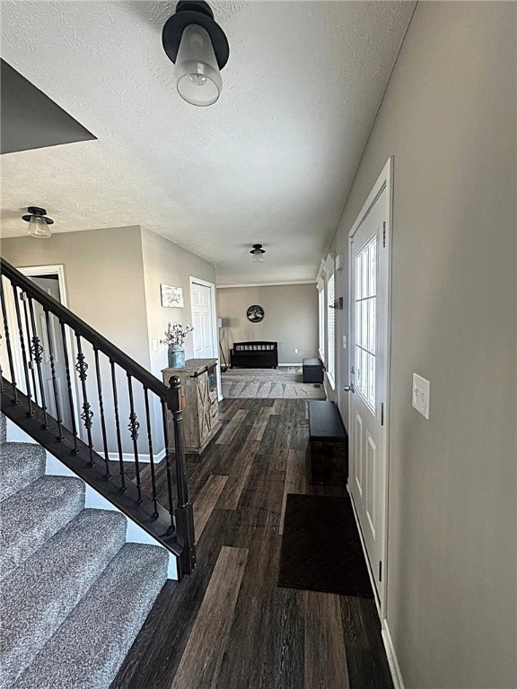 interior space featuring baseboards, a textured ceiling, and wood finished floors