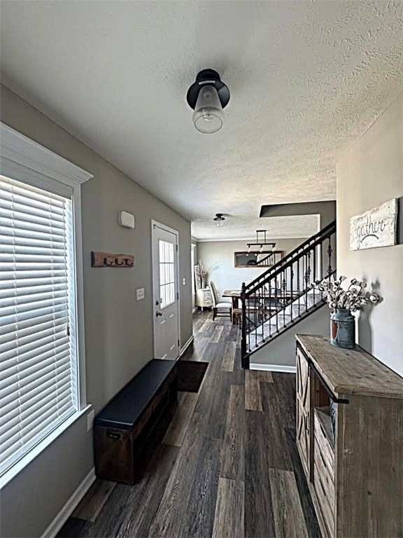 foyer featuring baseboards, a textured ceiling, stairs, and wood finished floors