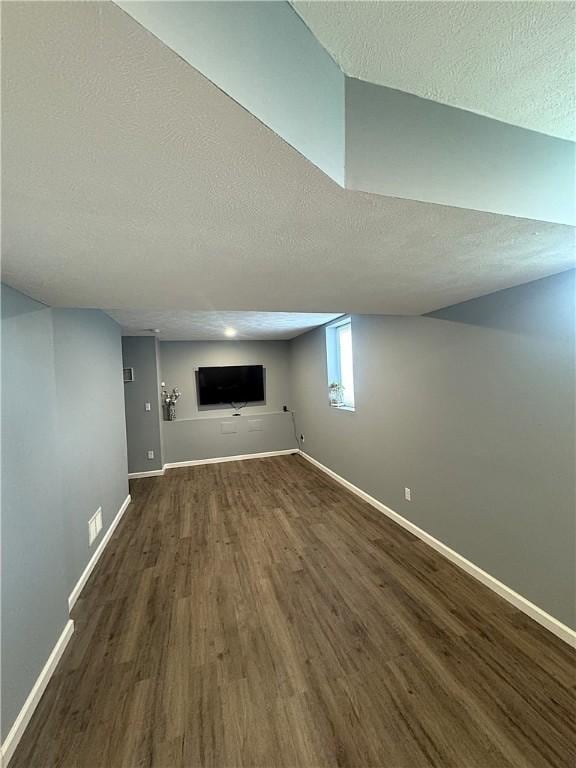 below grade area featuring baseboards, a textured ceiling, and wood finished floors