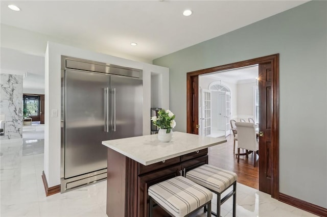 kitchen featuring marble finish floor, recessed lighting, light countertops, a center island, and stainless steel built in fridge