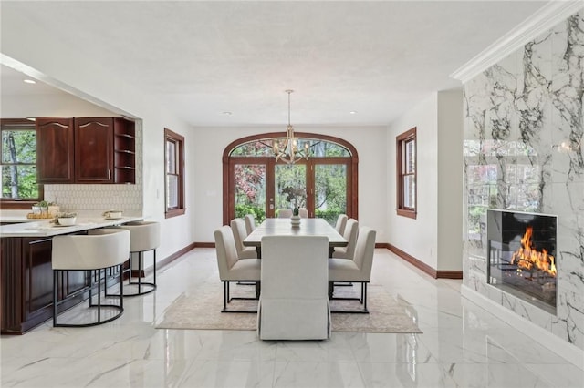 dining room with an inviting chandelier, plenty of natural light, marble finish floor, and a high end fireplace