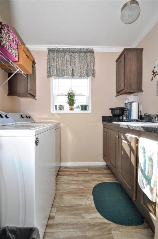 laundry area featuring crown molding, baseboards, light wood finished floors, and independent washer and dryer