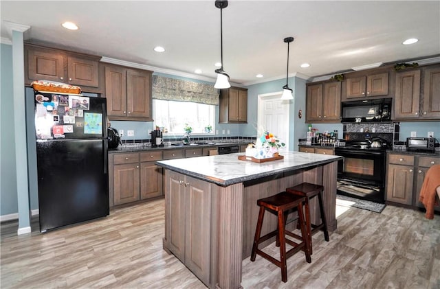 kitchen featuring a kitchen island, ornamental molding, a sink, and black appliances