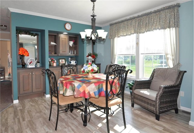 dining room with an inviting chandelier, ornamental molding, and light wood-style floors