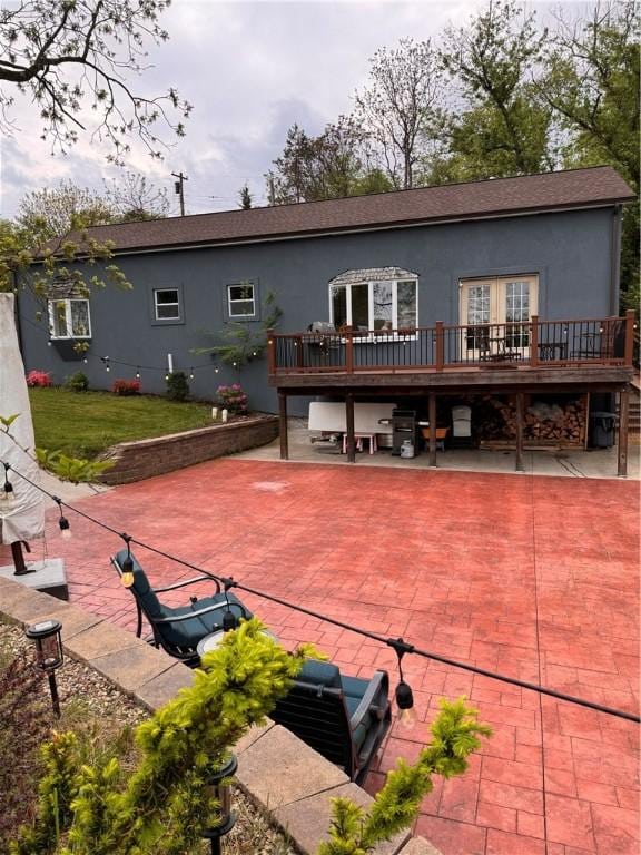 rear view of property featuring a wooden deck, roof with shingles, and stucco siding