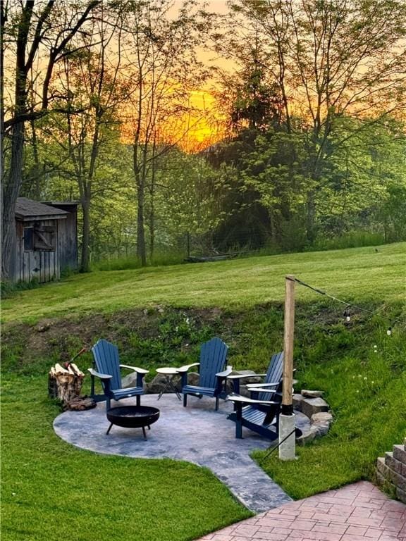 view of property's community with a lawn, a patio, and an outdoor fire pit
